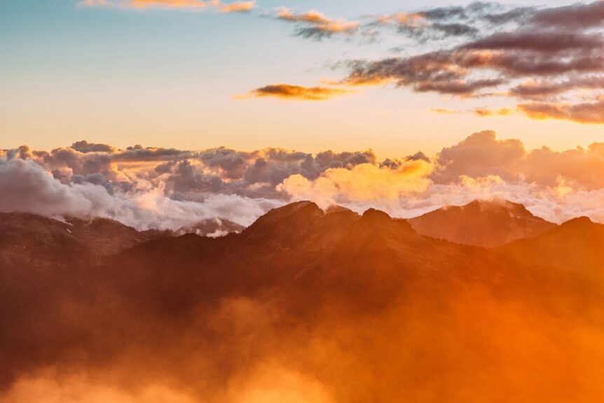 Sunset over mountains with colorful clouds.