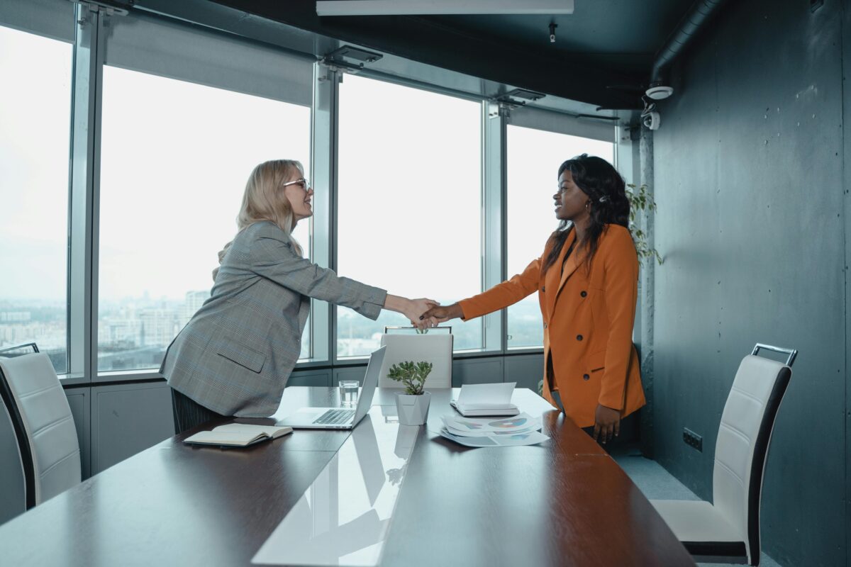 Two women shaking hands in office.