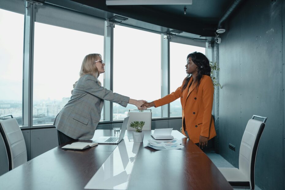 Two women shaking hands in office.